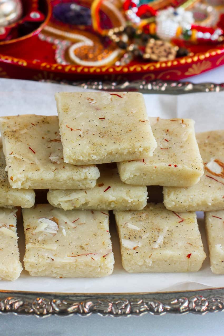 stack of badam burfi in a sliver tray.
