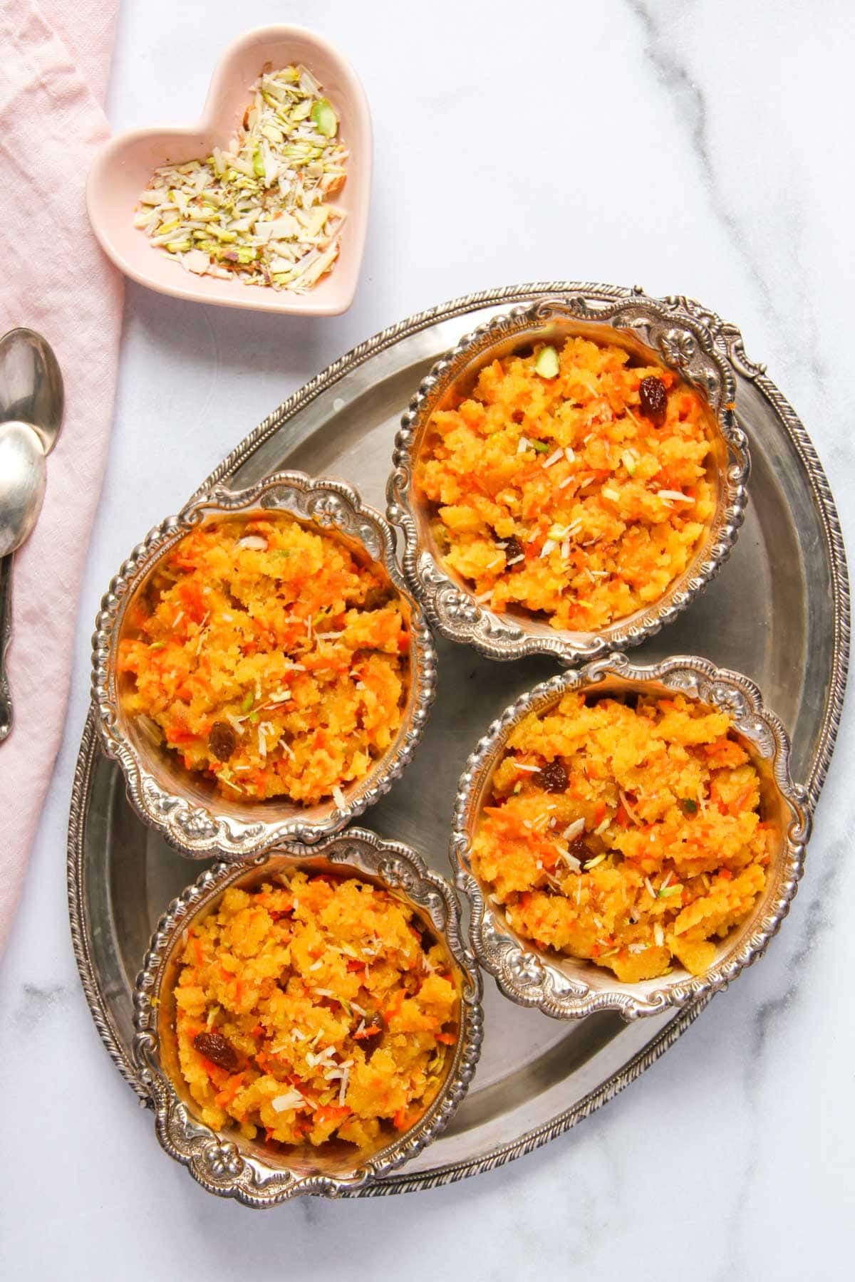 carrot sheera served in silver bowls.