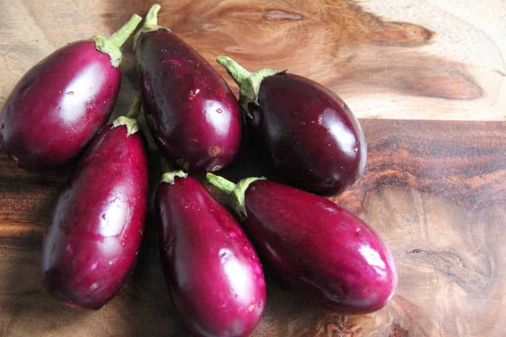 6 baby eggplant on a wooden cutting board