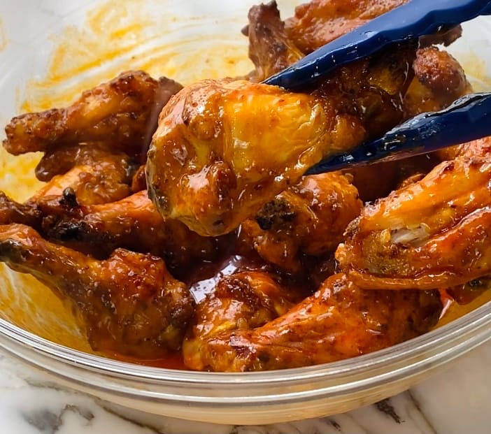 Tossing chicken wings in Frank's Red Hot Sauce