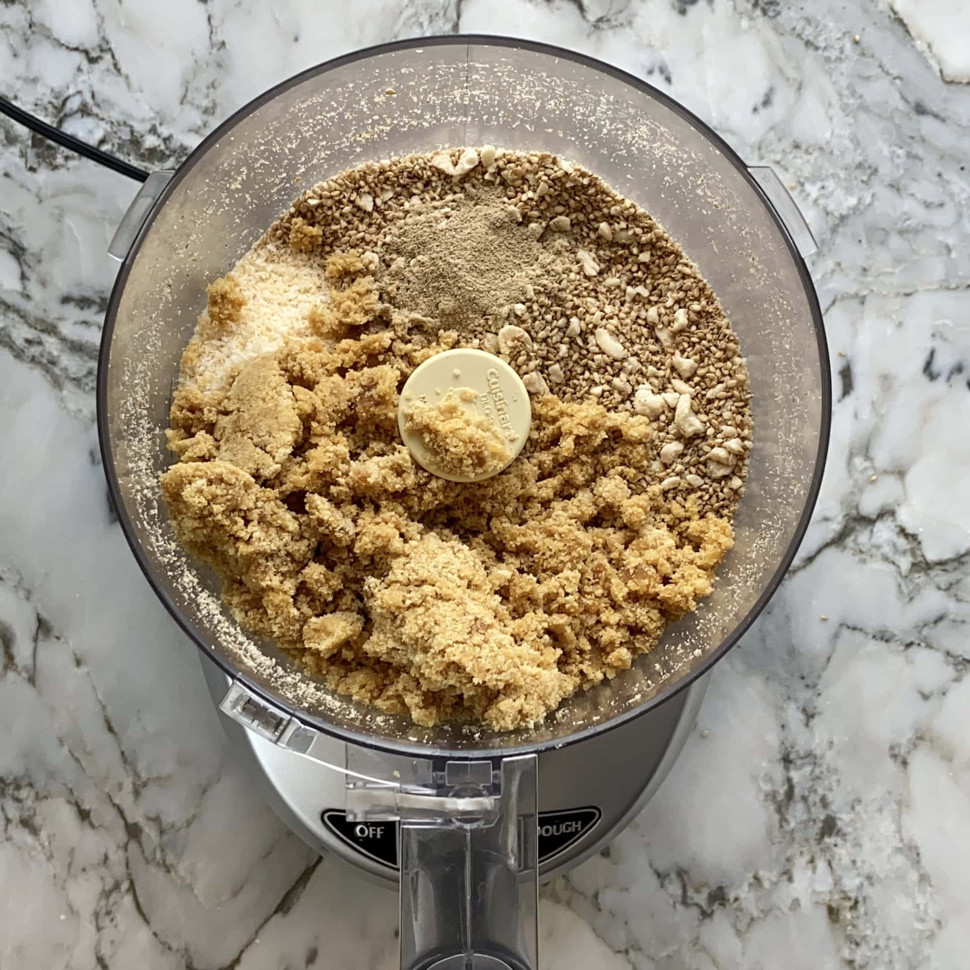 coarsely ground sesame seeds, peanuts, coocnut and jaggery in a food processor jar.