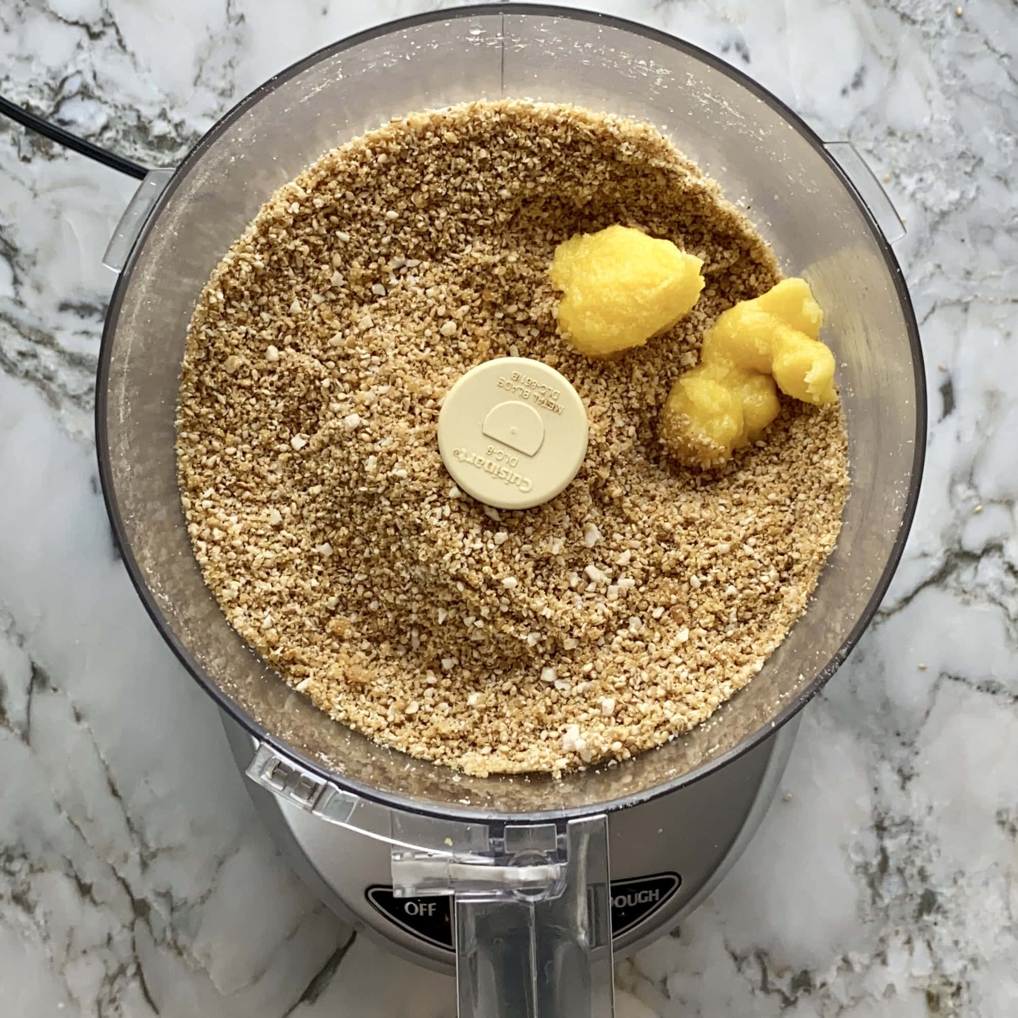 ghee added to sesame, jaggery mixture in a food processor jar.