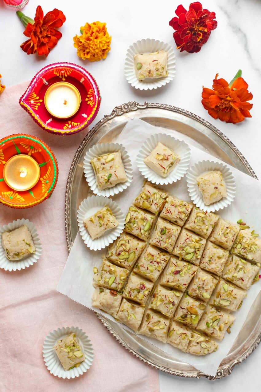 kalakand squares in a silver platter and paper cupcake liners