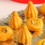 kisar malai modak and Peda garnished with saffron and pistachios.