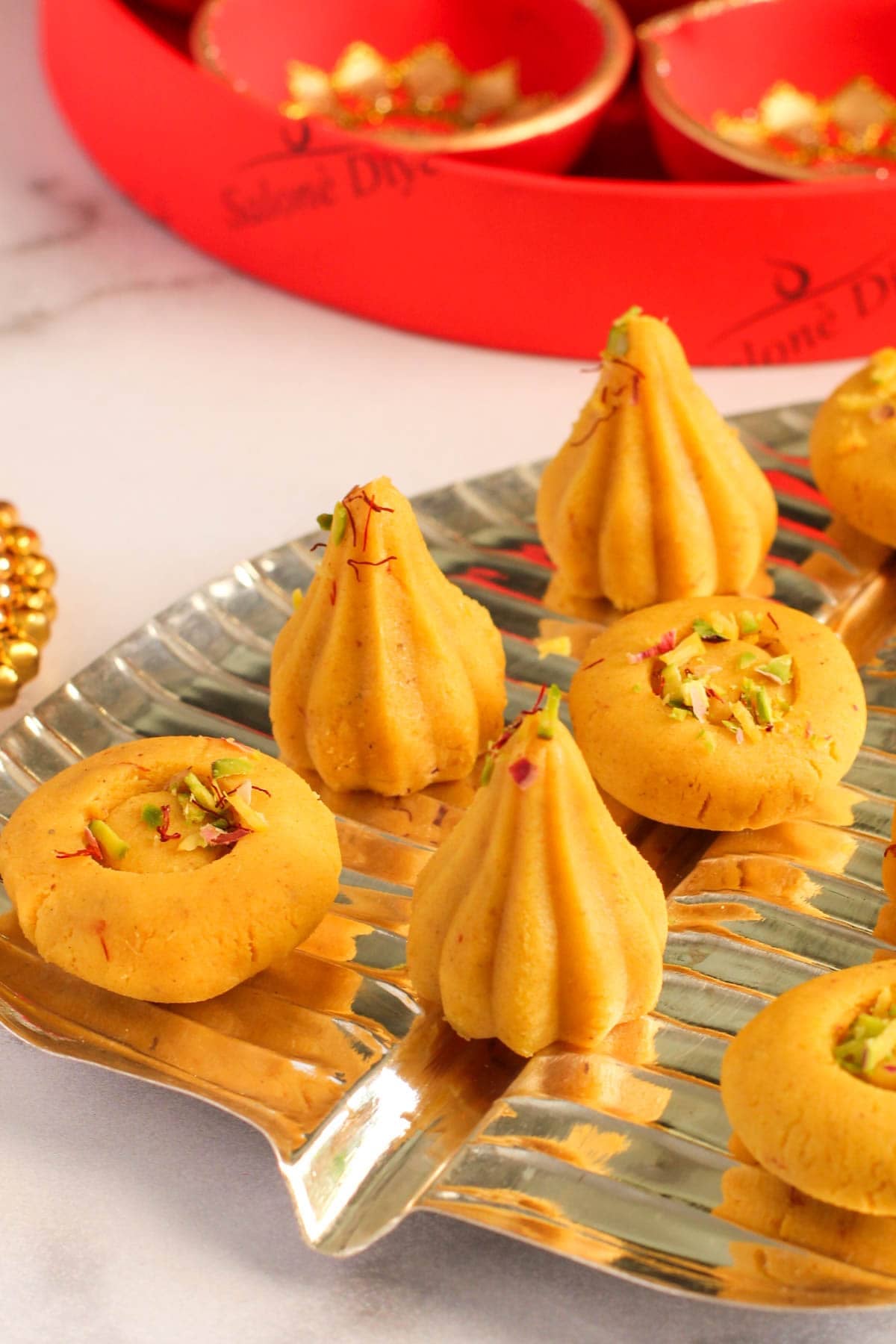 Kesar malai modak and peda in a silver platter. 