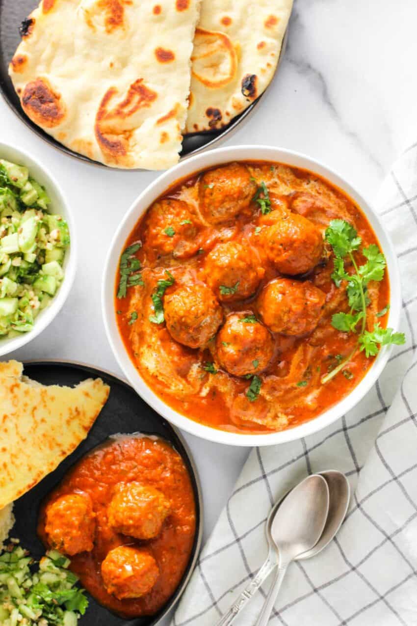 malai kofta servedin a white bowl  with naan next to it. 
