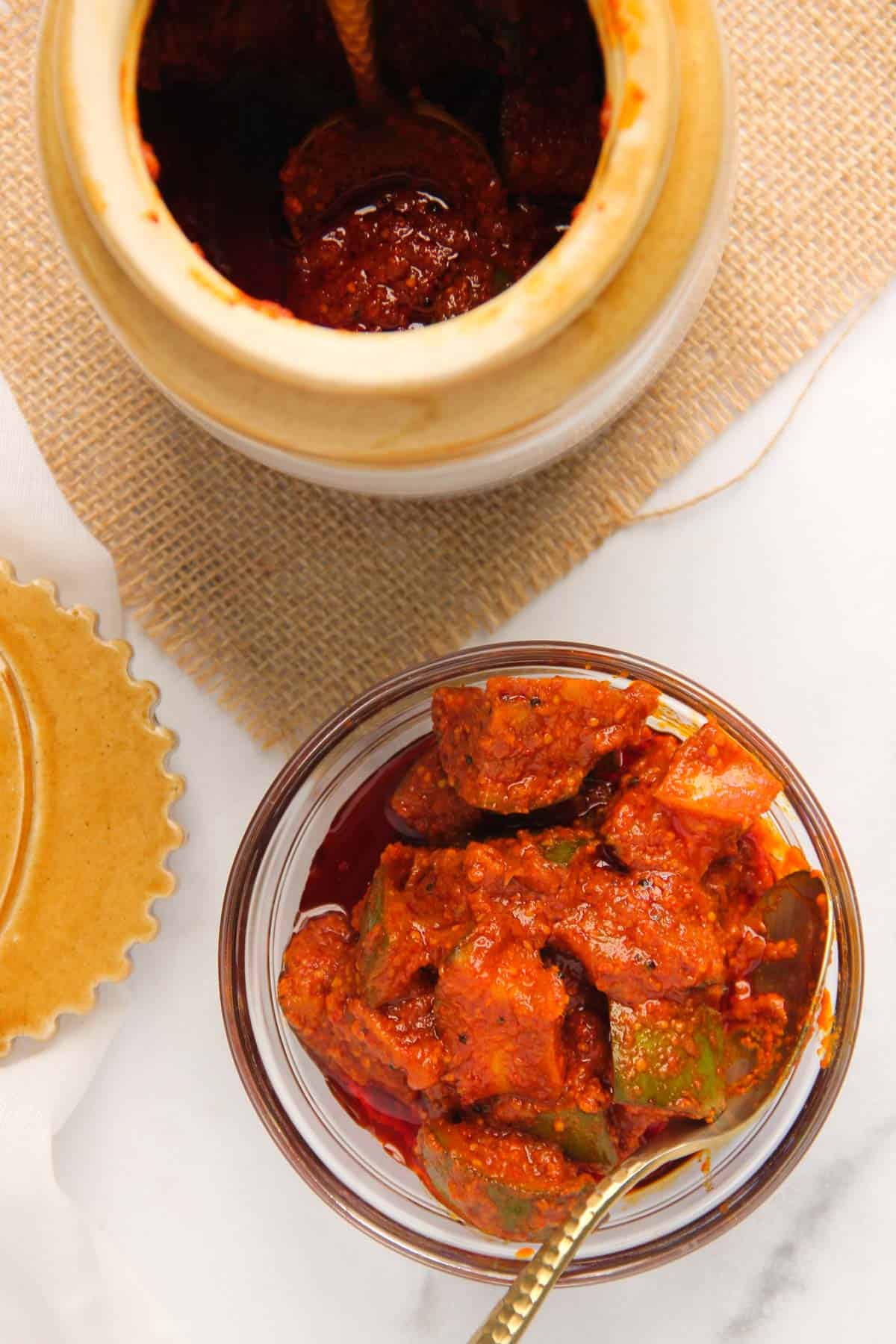 Indian mango pickle in a glass serving bowl and in a ceramic pickle jar