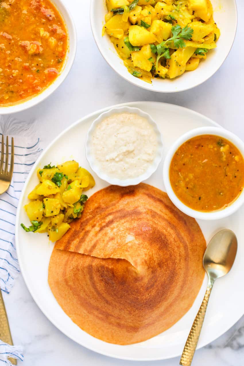 cone shaped quinoa dosa served with sambar, chutney & curried potatoes