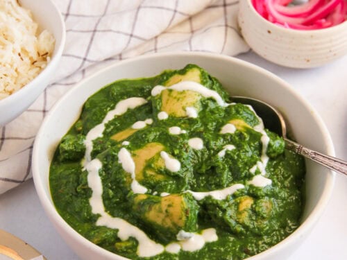 palak chicken garnished with cream in a serving bowl